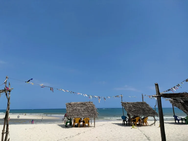 Sun loungers and thatched umbrellas on a white sand beach in Diani, Kenya